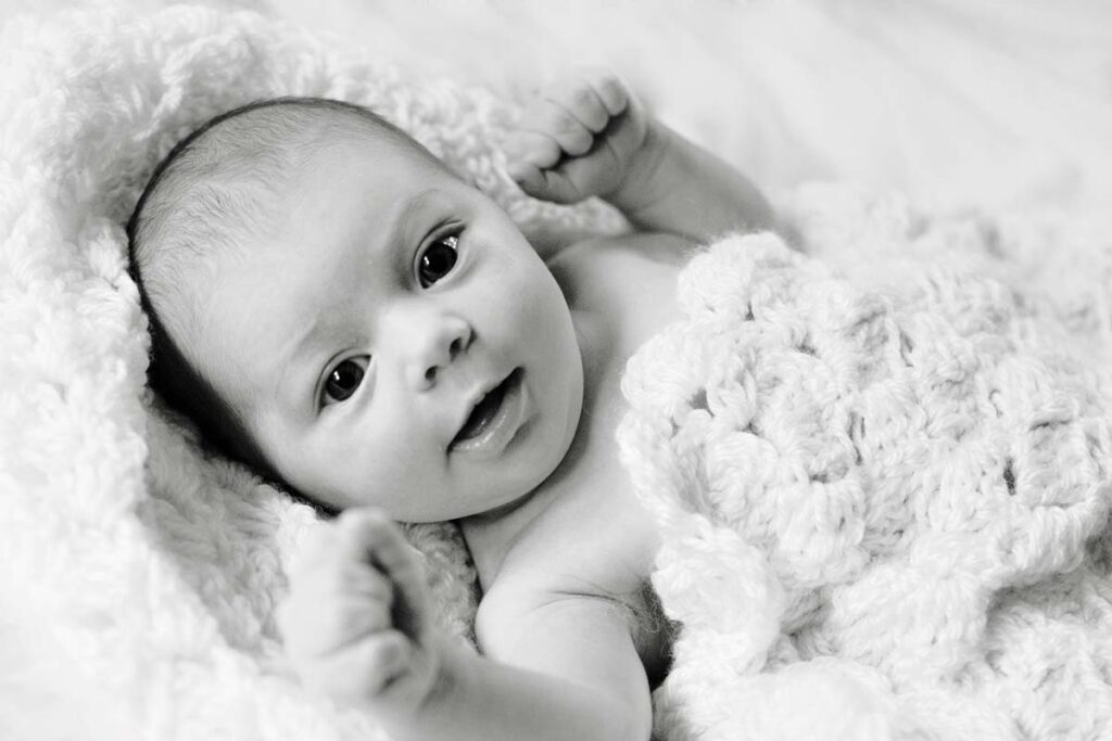 New baby smiling wrapped in crochet blanket