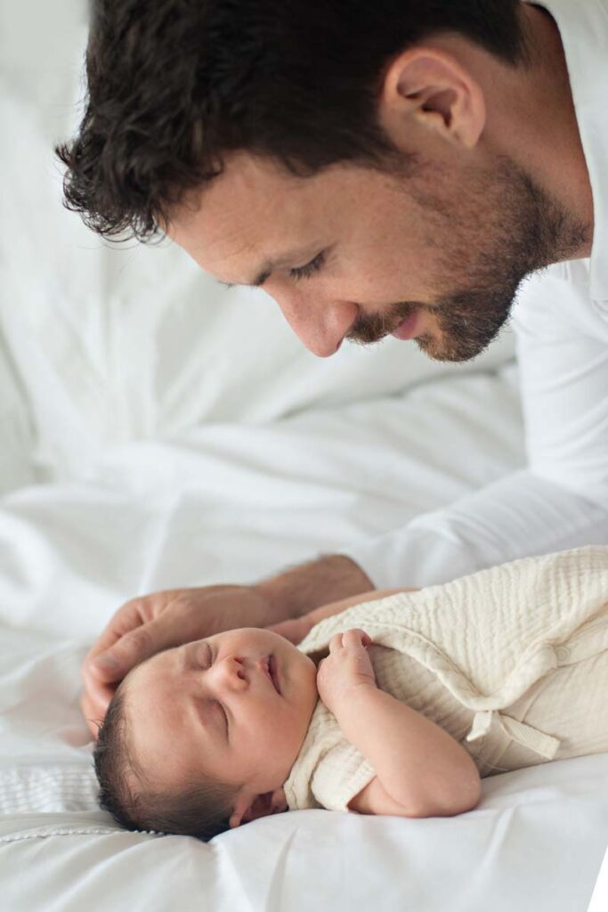 Dad looking down at newborn baby on bed