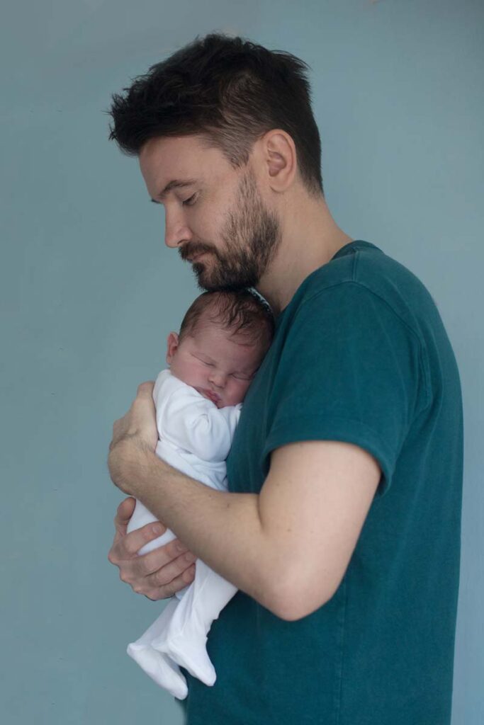Dad holding newborn baby against his chest