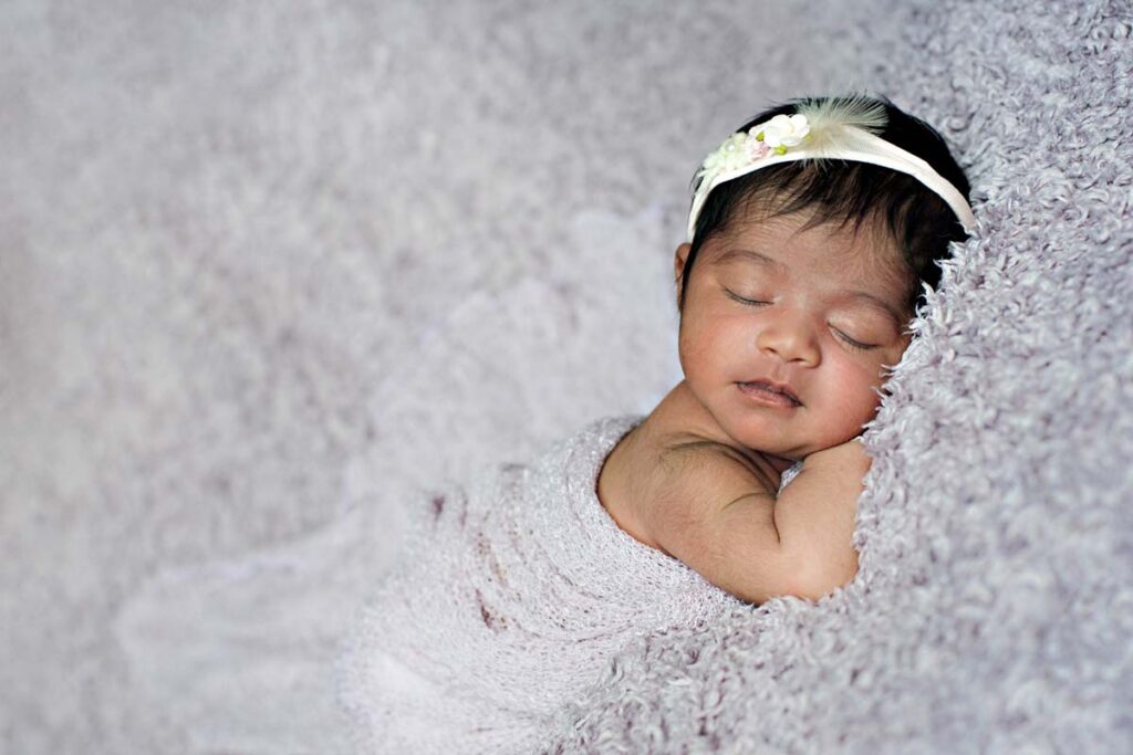 newborn baby girl on lilac blanket