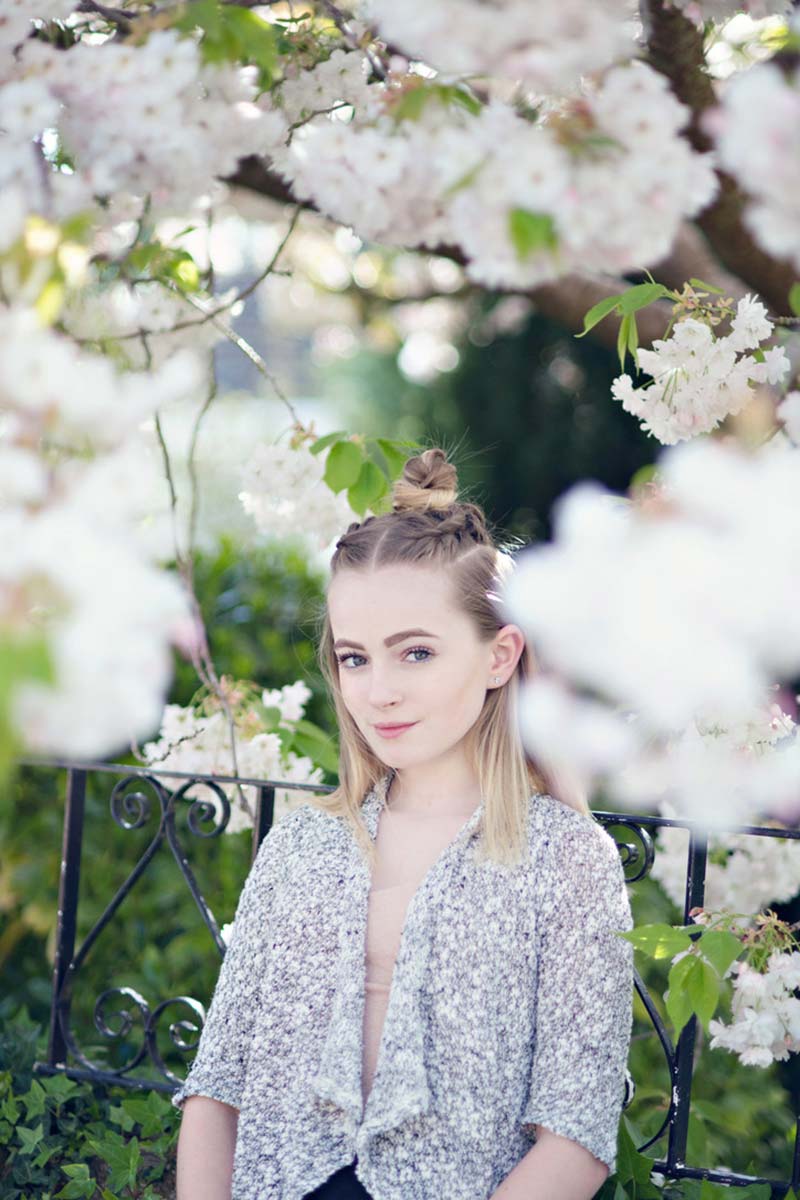 A young lady having her photo taken under the blossom tree